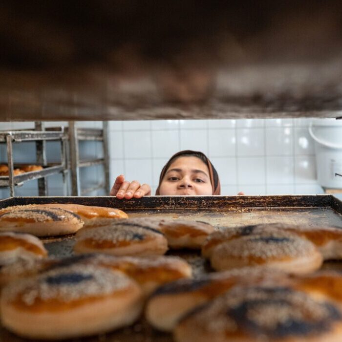 Bakker kijkt over de bakplaat de oven in