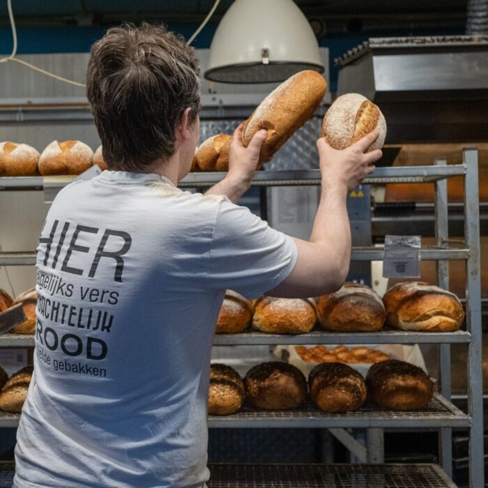 Bakker legt versgebakken broden op de afkoelwagen